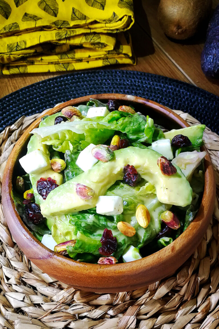 Ensalada roble tropical de lechuga, aguacate, arándanos secos, pistachos y queso griego vegano con aderezo de kiwi y mostaza